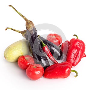 Tomatoes, red sweet peppers, red hot chilli peppers, violet eggplants, green zucchini in drops of water