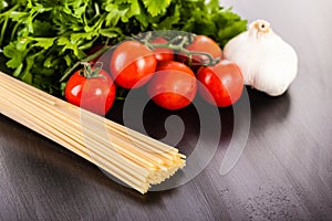 Tomatoes spaghetti garlic and parsley on wood