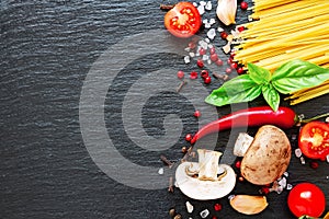 Tomatoes, spaghetti, spices, garlic and basil leaves on black background