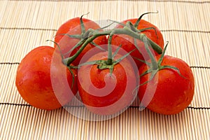 Tomatoes with sprigs on wooden background