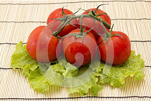 Tomatoes with sprigs on wooden background with lettuce