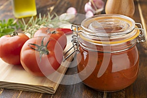 Tomatoes, tomato sauce, garlic, peppers and herbs over wood table