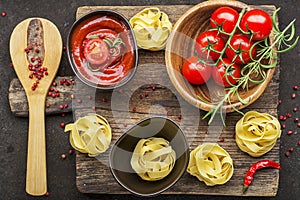 Tomatoes, tomato sauce, pasta, rosemary, red pepper for cooking dishes on a dark background. Top View.