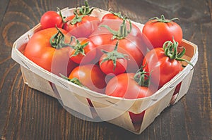 Tomatoes in a wattled basket on a wooden background/tomatoes in a wattled container on a dark wooden background, selective focus