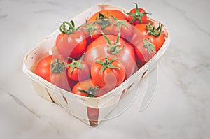 Tomatoes in a wattled box/tomatoes in a wattled box on a white marble background, selective focus