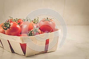 Tomatoes in a wattled container/tomatoes in a wattled container on a white marble background, selective focus and copyspace