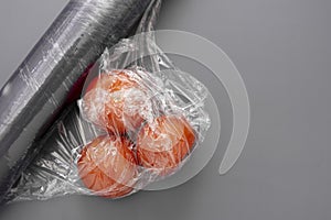 Tomatoes in wrapping plastic stretch film roll, abstract plastic waste concept. Copy space