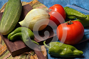 Tomatoes, zucchini, onion and pepper and wooden board photo