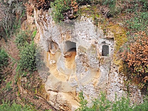 Tomb entrances in the cliff wall of a Via Cava, an ancient Etruscan road carved through tufo cliffs in Tuscany