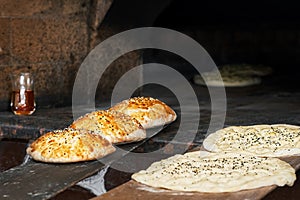 Tombik buns and Turkish Ramazan Pide bread before baking. Bread prepared for baking is in front of the stove. Morning pastries.