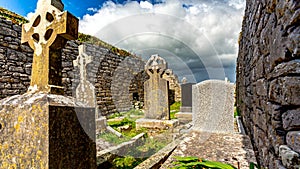 Tombs between ruined walls in the graveyard of the medieval church of Killilagh in the village of Doolin