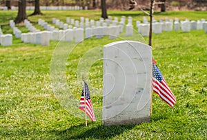 Tombstone at Arlington National Cemetery with US flags