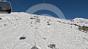 Tonale, Ponte di Legno, Italy. Chairlift with skiers moving to the top of the ski run in a wonderful sunny day