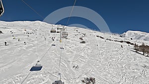 Tonale, Ponte di Legno, Italy. Chairlift with skiers moving to the top of the ski run in a wonderful sunny day