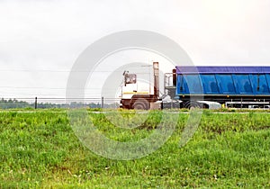 The tonar semitrailer semitrailer for transporting natural resources travels along the road in summer. Overcast sky