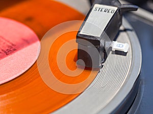 Tonearm of record-player on orange vinyl disc
