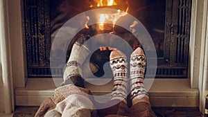 Toned closeup image of family wearing warm knitted socks lying by the fireplace at house