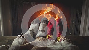 Toned closeup image of romantic couple warming under blanket at burning fireplace