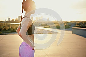 Toned fit young woman backlit by the sunrise