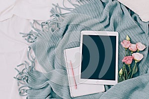 Toned Flat lay tablet and flowers on white blanket with turquoise plaid