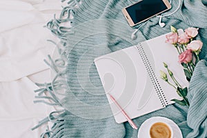 Toned Flat lay tablet, phone, cup of coffee and flowers on white blanket with turquoise plaid