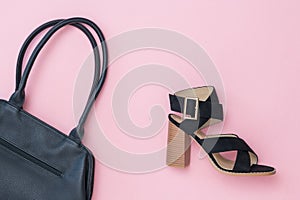 Toned image of a black women`s Shoe and a black bag on a pink background.