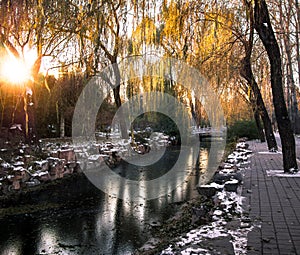 Toned image of a deserted alley with trees and a frozen canal in Beijing