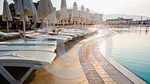 Toned image of empty sun bed at poolside at early morning. Nobody at swimming pool. Empty summer beach hotel resort