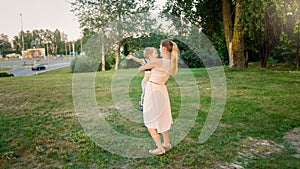 Toned image of happy smiling young mother holding and embracing her toddler son at park