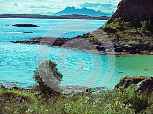 Toned image lonely man floating on the Norwegian sea through the Lofoten Islands against the backdrop of mountains and sky