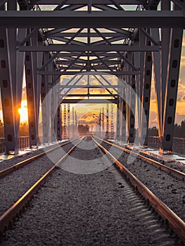 Toned image of the railway with sleepers and rail bridge on a background of multicolored sunset