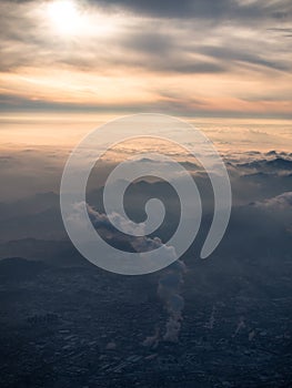 Toned image of smog over Beijing plant with a large column of toxic smoke in the background of a sunset with mountains