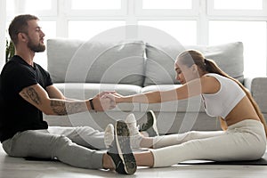 Toned man helping girlfriend stretch back after training