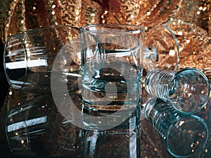 Toned photo of Close up empty glass goblets on glass table with golden blurry sparkles background