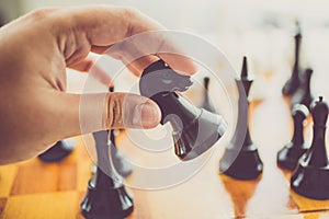 Toned photo of man making move with black horse at chess game