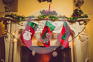 Toned photo of three red Christmas socks hanging on fireplace