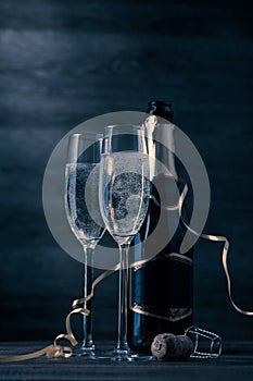 Toned photo of two wine glasses with sparkling champagne, bottle, cork