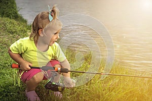 Toned portrait of a baby girl with tackles on real fishing at lake photo