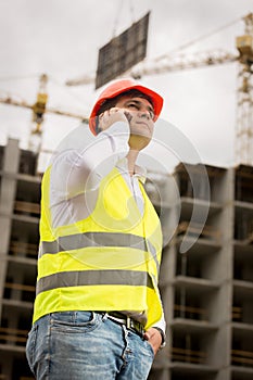 Toned portrait of construction engineer talking by phone on cons