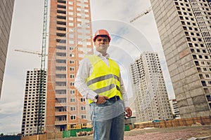 Toned portrait of engineer posing against buildings under construction