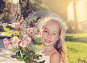 Toned portrait of happy beautyful little Girl hold roses and smile at summer day