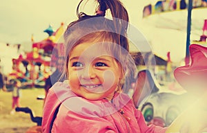 Toned portrait of happy cute smiling girl riding on carousel