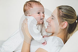 Toned portrait of lying young woman holding her 3 months old baby