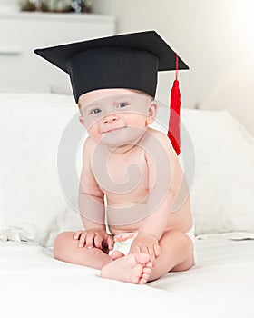 Toned portrait of smiling baby boy in graduation hat looking in