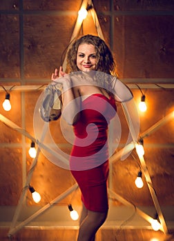 Toned portrait of smiling woman in dress taking shoes off against big glowing star