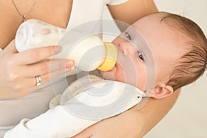 Toned portrait of young mother holding her baby boy and feeding