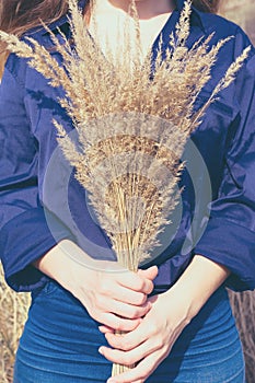 Toned vertical photo of young woman with long blond hair in blue shirt and jeans