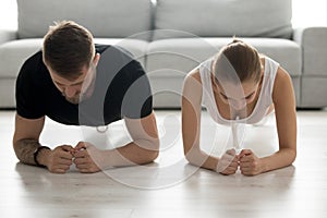 Toned young couple stand in forearm plank training together