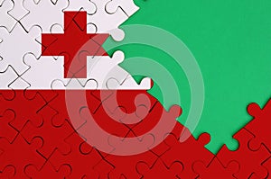 Tonga flag is depicted on a completed jigsaw puzzle with free green copy space on the right side