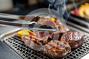 Tongs gripping meat, emphasizing action and functionality during cooking process